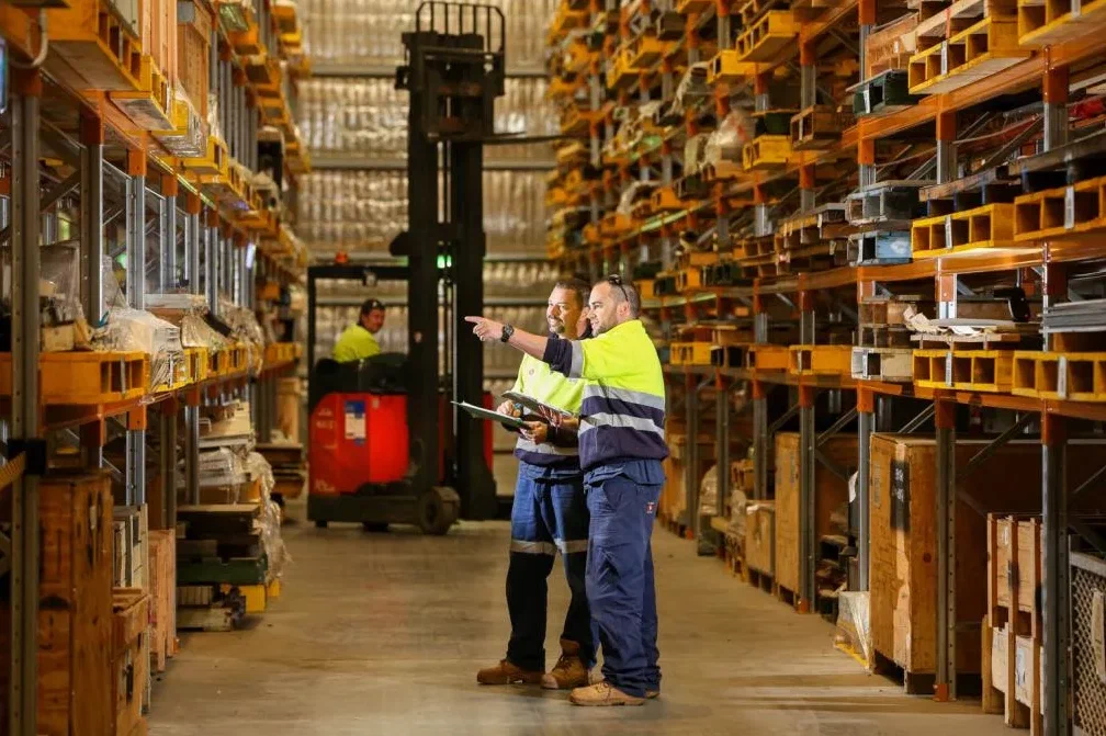 Two workers talking beside industrial storage racks